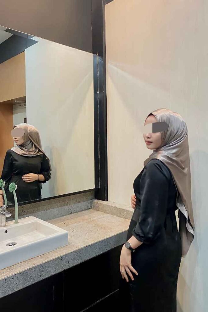 Malay KL Escort, Eika, in a black dress and hijab, reflected in a mirror. Kuala Lumpur Call Girl