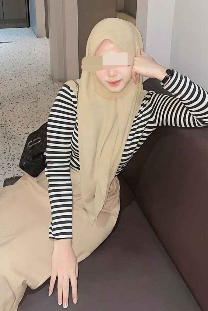 Eika, a stunning Malay Escort in KL, poses in a striped shirt and hijab. Call Girl Malaysia Escort Kuala Lumpur Escort.
