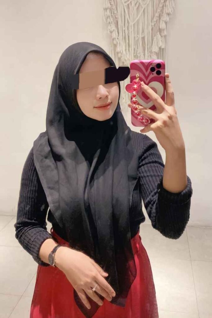 Malay woman in hijab with phone. Escort services in KL, Malaysia. Call Girl.
